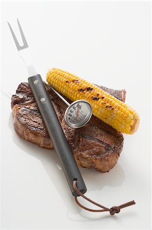 Beef steak with corn on the cob, carving fork & thermometer Stock Photo - Premium Royalty-Free, Code: 659-03526963