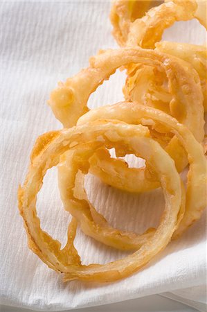 panatura - Deep-fried onion rings on kitchen paper (close-up) Fotografie stock - Premium Royalty-Free, Codice: 659-03526994