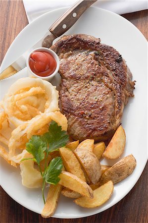 simsearch:659-08147298,k - Rib-eye steak with onion rings, ketchup and potato wedges Foto de stock - Sin royalties Premium, Código: 659-03527000