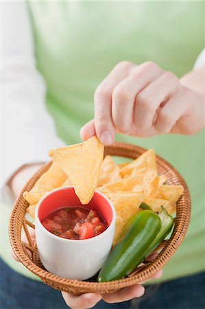 simsearch:659-03527105,k - Woman holding basket of nachos with salsa and chilli Foto de stock - Royalty Free Premium, Número: 659-03527099