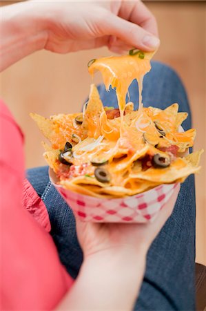 Hand taking nachos with melted cheese from cardboard container Stock Photo - Premium Royalty-Free, Code: 659-03527124