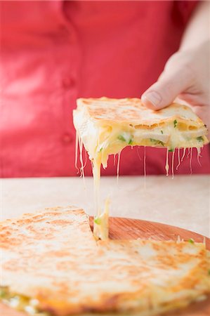 Hand taking piece of quesadilla from wooden board Stock Photo - Premium Royalty-Free, Code: 659-03527122