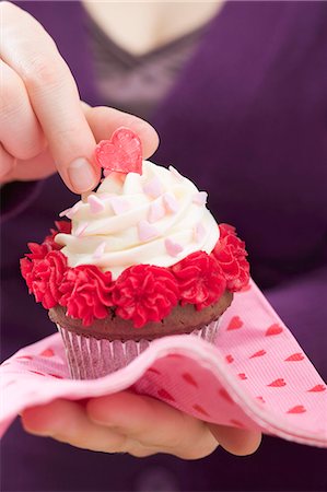 Woman holding Valentine's Day cupcake on paper napkin Stock Photo - Premium Royalty-Free, Code: 659-03527277