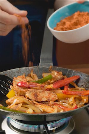 simsearch:659-06901276,k - Adding chilli powder to chicken with onions and peppers Stock Photo - Premium Royalty-Free, Code: 659-03527298