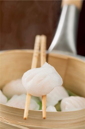 Dim sum on chopsticks and in bamboo steamer Stock Photo - Premium Royalty-Free, Code: 659-03527316