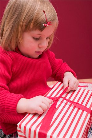 simsearch:659-03521663,k - Small girl undoing ribbon on Christmas parcel Foto de stock - Sin royalties Premium, Código: 659-03527860