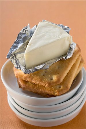 Processed cheese in foil on crackers in stacked dishes Foto de stock - Sin royalties Premium, Código: 659-03528068