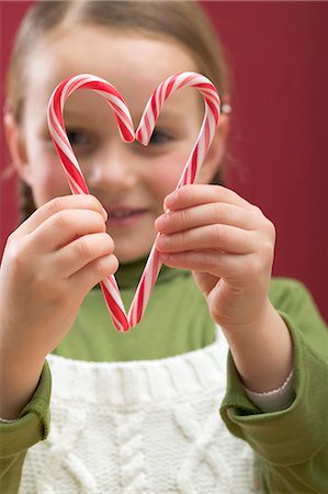 simsearch:659-01866689,k - Small girl looking through heart made from two candy canes Foto de stock - Royalty Free Premium, Número: 659-03528106