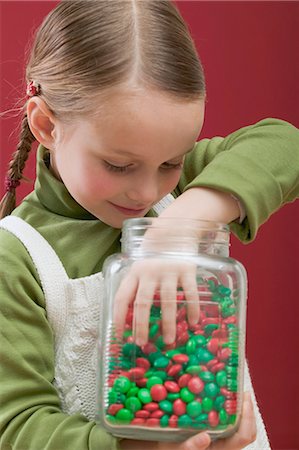 Small girl reaching into jar of chocolate beans Stock Photo - Premium Royalty-Free, Code: 659-03528101