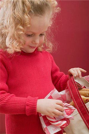 Small girl holding bag of candy canes and biscuits Stock Photo - Premium Royalty-Free, Code: 659-03528148