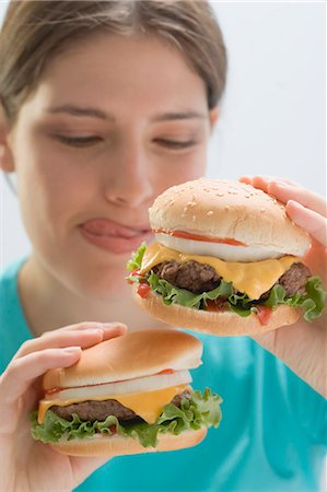 Young woman holding two succulent cheeseburgers Stock Photo - Premium Royalty-Free, Code: 659-03528377