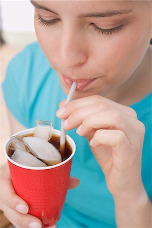 Young woman drinking cola through a straw Stock Photo - Premium Royalty-Free, Code: 659-03528385