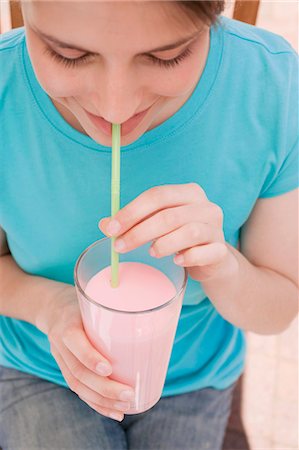 smoothie in cocktail glass - Young woman drinking strawberry milk through a straw Stock Photo - Premium Royalty-Free, Code: 659-03528380