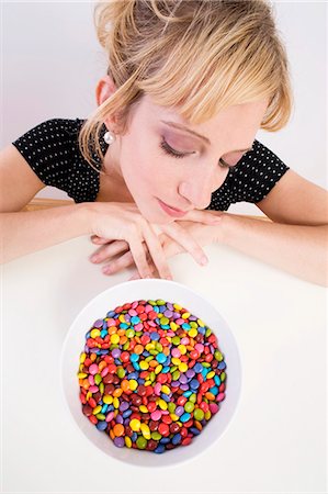 simsearch:659-03522828,k - Woman looking pensively at coloured chocolate beans Stock Photo - Premium Royalty-Free, Code: 659-03528816