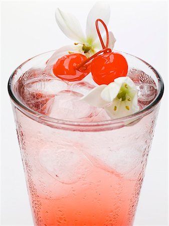 Tequila Sunrise with ice cubes, cocktail cherries & flowers Stock Photo - Premium Royalty-Free, Code: 659-03528921