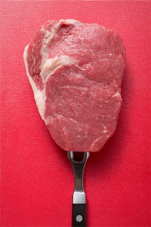 Raw beef steak on meat fork Stock Photo - Premium Royalty-Free, Code: 659-03529004