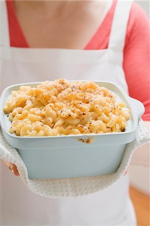 pasta gratin - Woman holding baking dish of macaroni cheese Stock Photo - Premium Royalty-Free, Code: 659-03529032