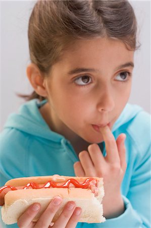 sausage, bun - Little girl eating hot dog with ketchup Stock Photo - Premium Royalty-Free, Code: 659-03529066