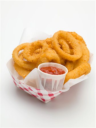 Deep-fried onion rings with ketchup in paper dish Stock Photo - Premium Royalty-Free, Code: 659-03529166