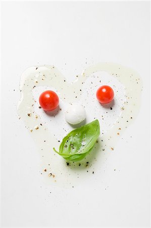 Tomatoes, mozzarella, basil, oil and spices forming a face Stock Photo - Premium Royalty-Free, Code: 659-03529237