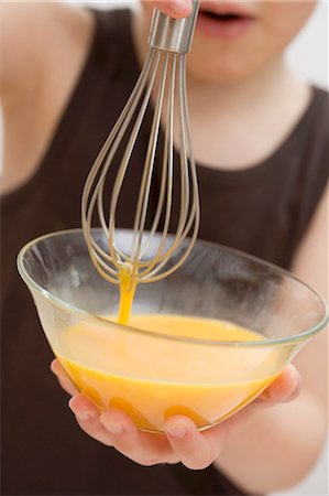 simsearch:659-03529414,k - Child holding bowl of egg yolks and whisk Fotografie stock - Premium Royalty-Free, Codice: 659-03529407