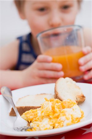 simsearch:659-03529414,k - Scrambled egg & toast, little boy in background drinking juice Fotografie stock - Premium Royalty-Free, Codice: 659-03529414