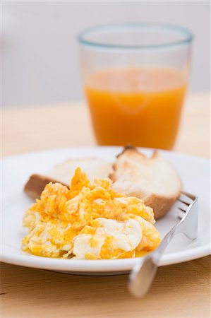 scrambled - Scrambled egg, toast and glass of fruit juice Foto de stock - Sin royalties Premium, Código: 659-03529410