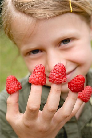 Girl with raspberries on her fingers Stock Photo - Premium Royalty-Free, Code: 659-03529439