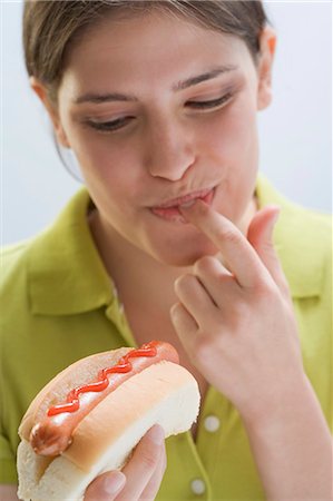 en-cas - Jeune femme dégustation ketchup sur hot dog Photographie de stock - Premium Libres de Droits, Code: 659-03529459