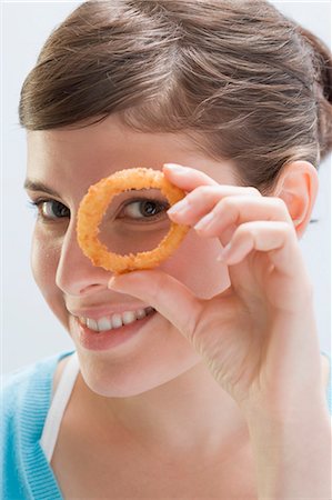 Young woman looking through deep-fried onion ring Foto de stock - Sin royalties Premium, Código: 659-03529465