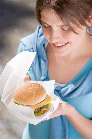 Young woman with cheeseburger out of doors Stock Photo - Premium Royalty-Free, Code: 659-03529475