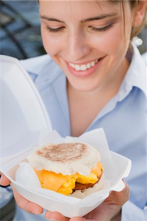 poliestireno - Young woman holding English muffin with cheese, scrambled egg & bacon Foto de stock - Sin royalties Premium, Código: 659-03529478