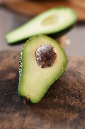 Avocado, halved, on old chopping board Stock Photo - Premium Royalty-Free, Code: 659-03529523