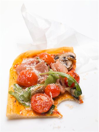 pizza piece - Slice of pizza with ham, tomatoes, mushrooms, rocket, a bite taken Stock Photo - Premium Royalty-Free, Code: 659-03529700
