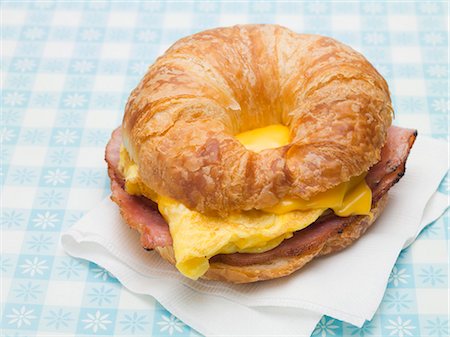 Croissant with scrambled egg, cheese & bacon on paper napkin Foto de stock - Sin royalties Premium, Código: 659-03529720