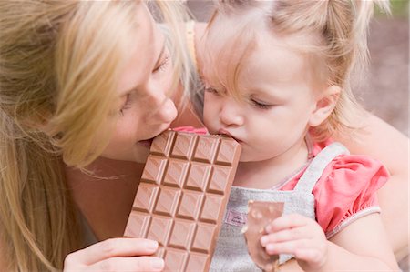 pictures of chocolate bars - Mother and young daughter biting into a bar of chocolate Stock Photo - Premium Royalty-Free, Code: 659-03529831