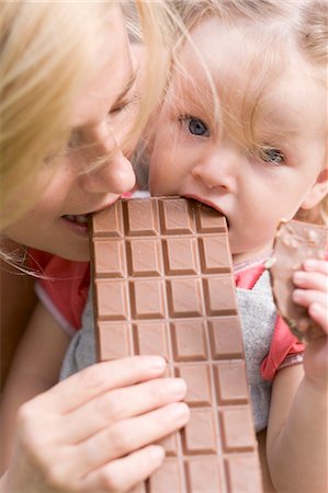 Mother and young daughter biting into a bar of chocolate Stock Photo - Premium Royalty-Free, Code: 659-03529832