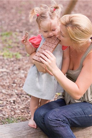 Mother and young daughter biting into a bar of chocolate Stock Photo - Premium Royalty-Free, Code: 659-03529833