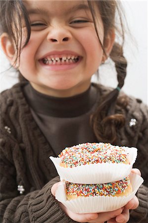 Giggling girl holding two doughnuts with sprinkles Stock Photo - Premium Royalty-Free, Code: 659-03521679