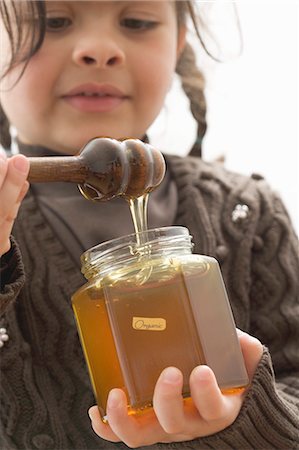 simsearch:659-03521663,k - Girl taking organic honey out of jar with honey dipper Foto de stock - Sin royalties Premium, Código: 659-03521672