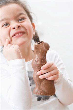 Girl holding chocolate Easter Bunny with its ear bitten off Stock Photo - Premium Royalty-Free, Code: 659-03521745