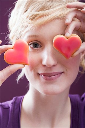 Young woman with two heart-shaped biscuits in front of her eyes Stock Photo - Premium Royalty-Free, Code: 659-03521810