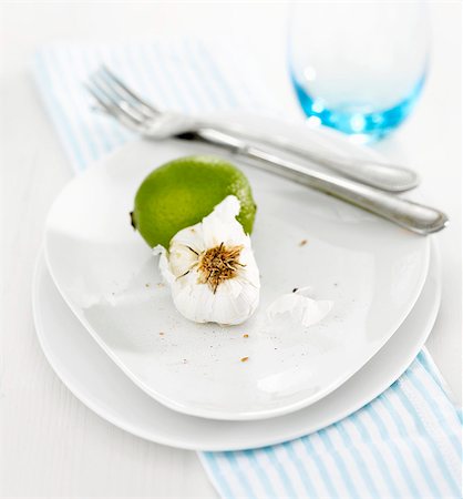 Lime and garlic with knife and fork on white plate Stock Photo - Premium Royalty-Free, Code: 659-03521931