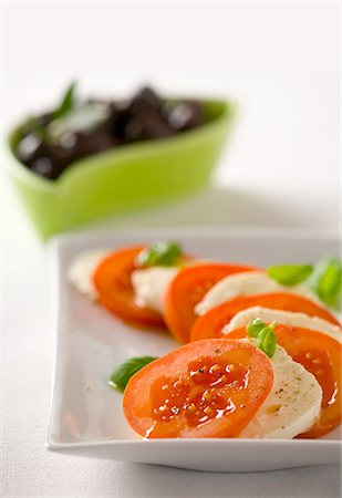 Tomatoes with mozzarella and basil and black olives Stock Photo - Premium Royalty-Free, Code: 659-03522205