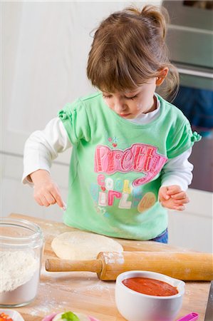 Small girl dusting pizza dough with flour Stock Photo - Premium Royalty-Free, Code: 659-03522219