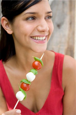 Young woman with tomato and mozzarella skewer Stock Photo - Premium Royalty-Free, Code: 659-03522651