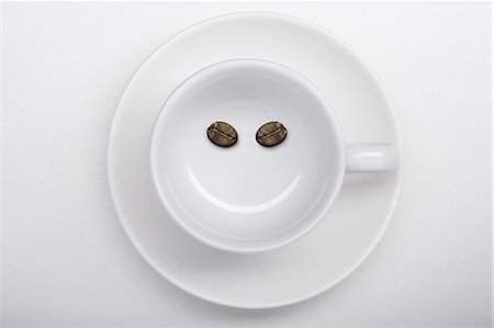 simsearch:400-06461761,k - A coffee cup with two coffee beans making a smiley face Fotografie stock - Premium Royalty-Free, Codice: 659-03522696