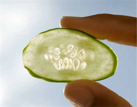 Thin slice of cucumber between someone's finger and thumb Stock Photo - Premium Royalty-Free, Code: 659-03522821