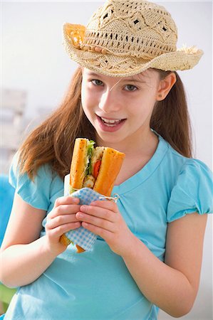 Girl in hat eating fish and salad sandwich at picnic Stock Photo - Premium Royalty-Free, Code: 659-03523088