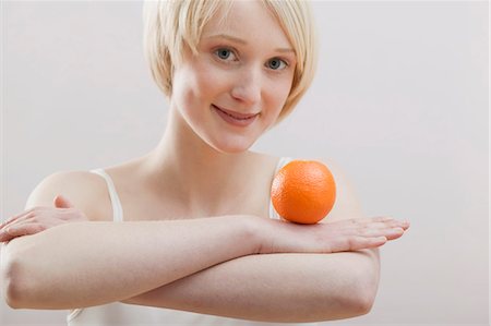 simsearch:659-01855145,k - Young woman balancing an orange on folded arms Foto de stock - Royalty Free Premium, Número: 659-03523376